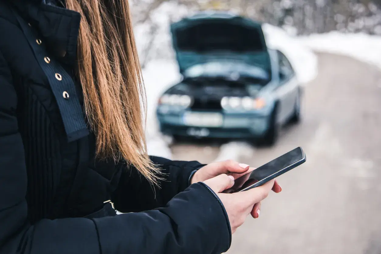 mujer con coche averiado llamando al seguro